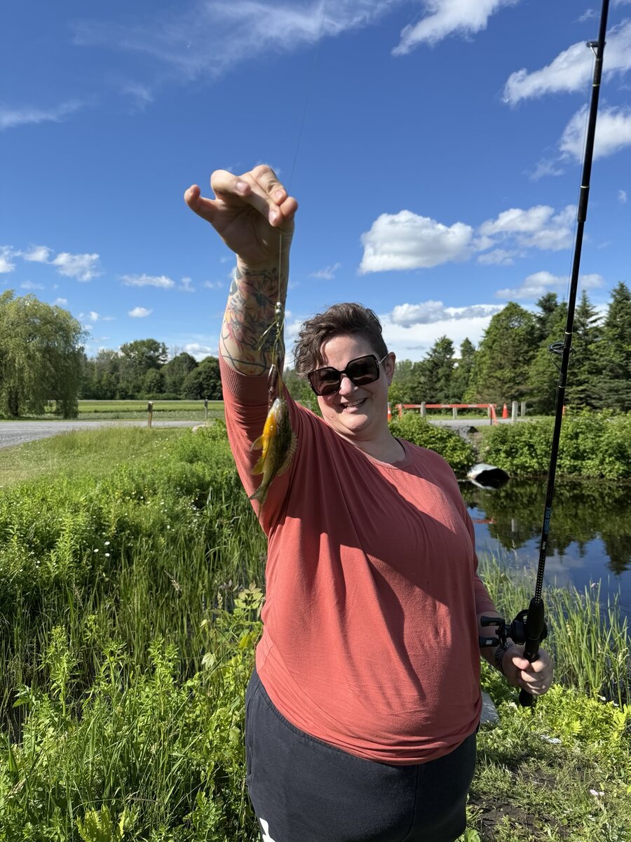 Jennifer smiling while holding up a small fish